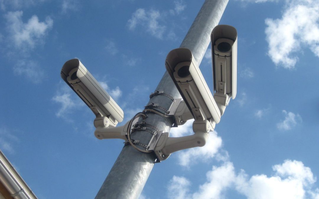 Symbnolbild drei Überwachungskameras an einem Mast vor blauem Himmel.